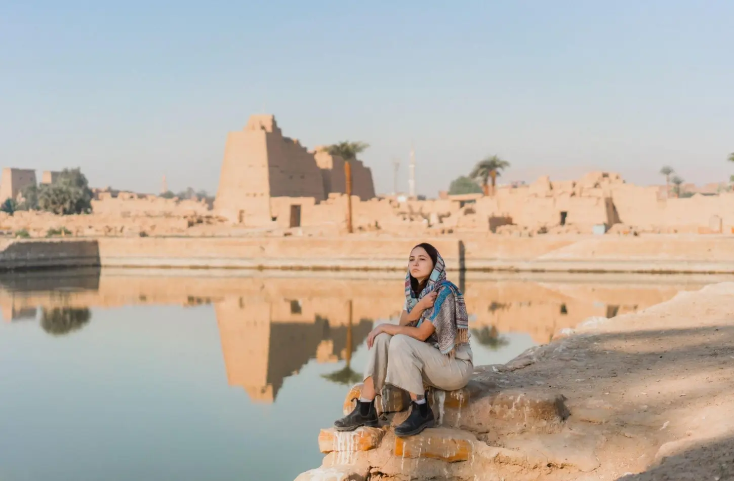 Woman resting by a reflection pool at the ancient Karnak Temple